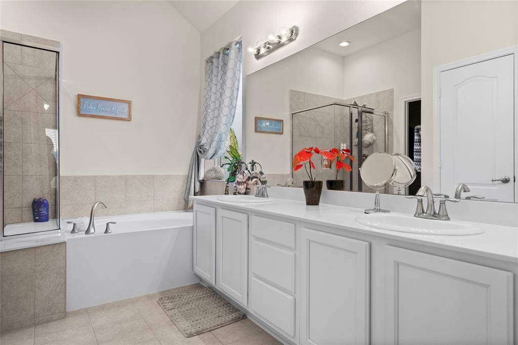 The primary bathroom features a spacious layout with a dual-sink vanity, a large mirror, a bathtub with surrounding tiles, and a separate glass-enclosed shower.