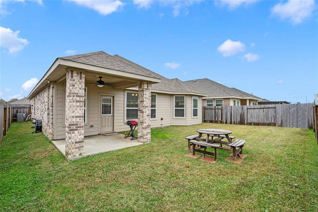 Enjoy a cozy backyard with a covered patio featuring brick columns with a ceiling fan.