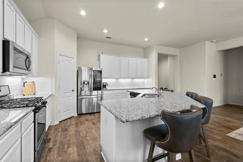 Modern kitchen with granite countertops, stainless steel appliances, and a central island with bar seating.