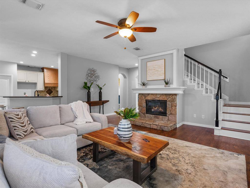 Living area showcasing a stone fireplace and open layout to the kitchen."