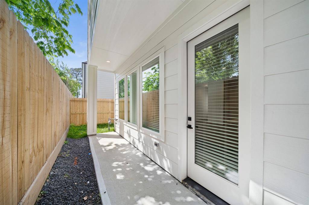 Fully fenced, covered patio with green space around the corner.