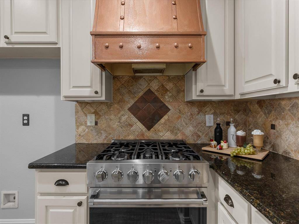 Gourmet kitchen featuring a professional-grade range and custom copper vent hood
