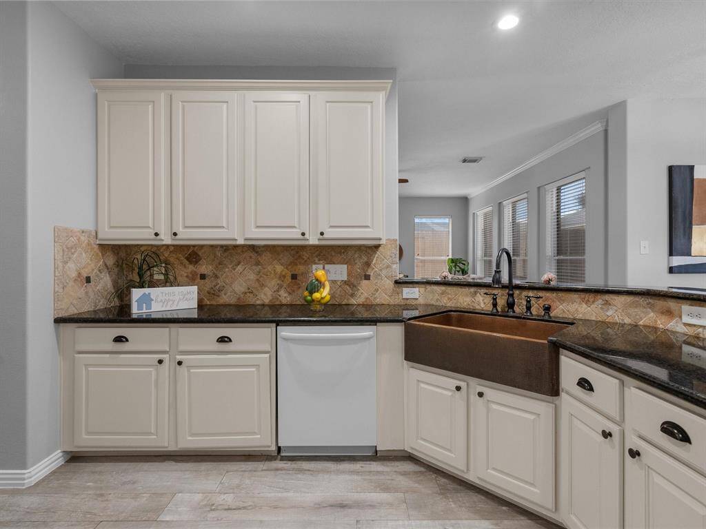 Charming kitchen with a farmhouse sink, granite countertops, and tile backsplash