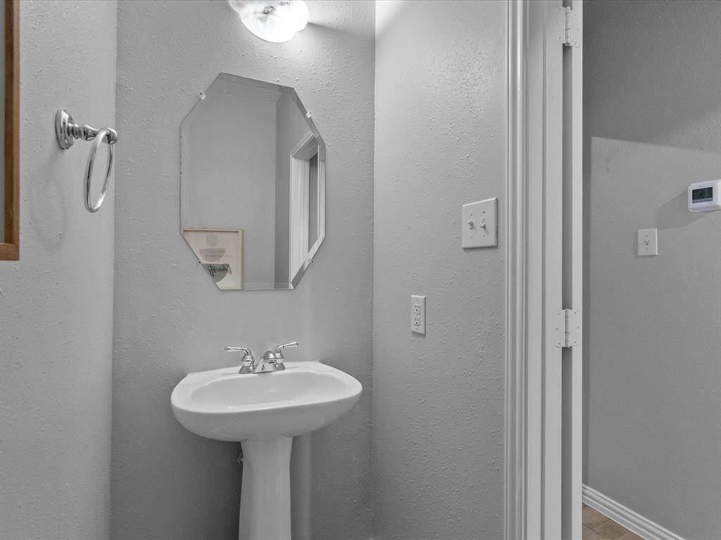 Conveniently located powder room with a pedestal sink and stylish mirror