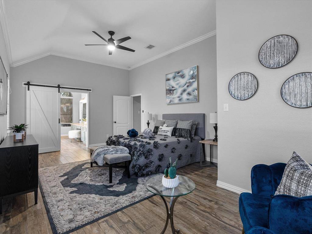 Spacious primary bedroom with barn-style doors leading to the ensuite bathroom