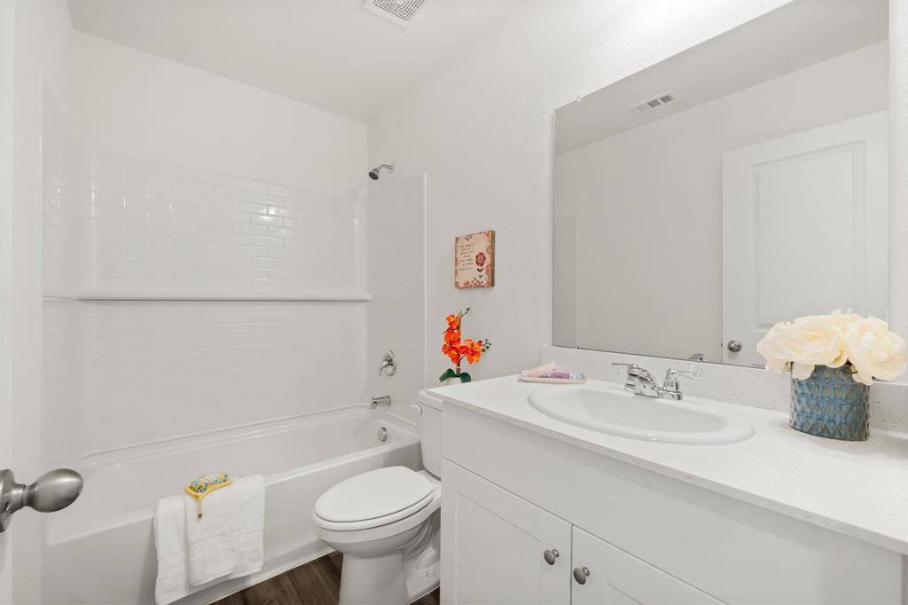 Light and bright secondary bathroom is located between the two secondary bedrooms and features white cabinets and quartz countertops.