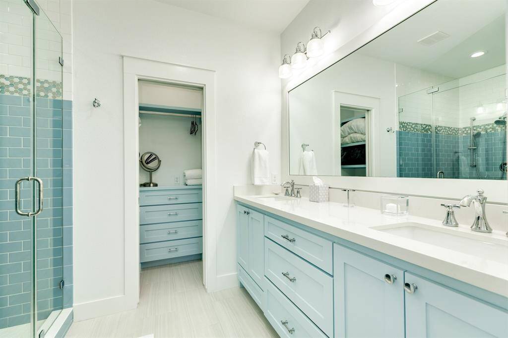 This en-suite bathroom has a walk-in shower and a large walk-in closet with double vanity sinks