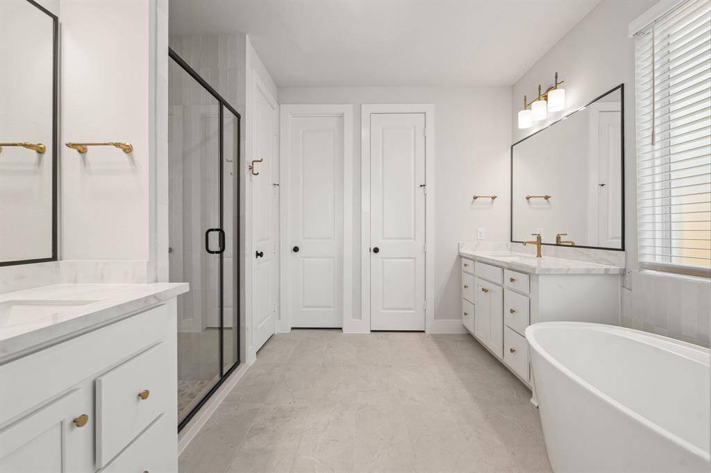 The main bathroom offers a luxurious experience with an enlarged walk-in shower featuring sleek glass doors and modern fixtures. It also includes separate sinks, providing ample space and convenience for two people.
