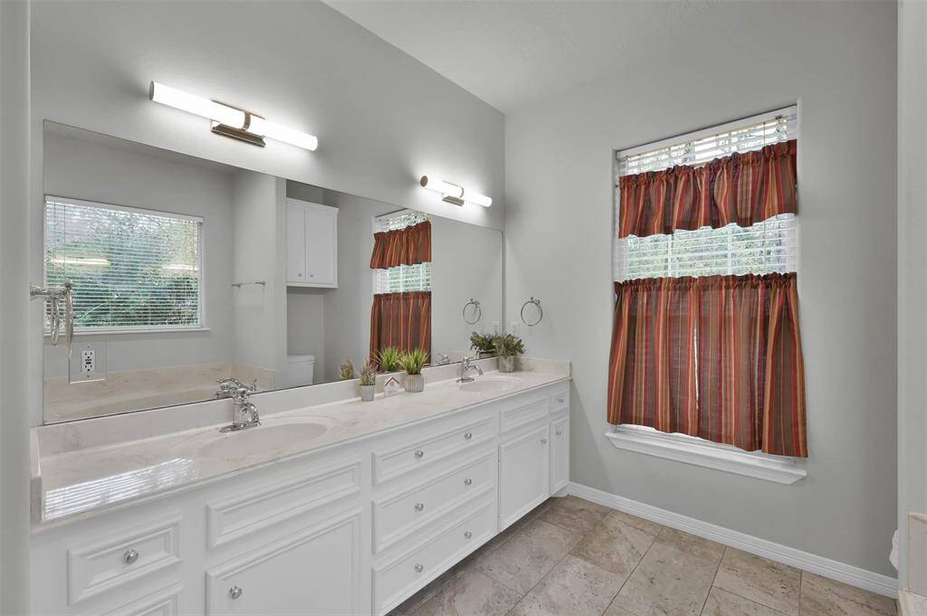 Bright and inviting primary bathroom featuring double sinks and abundant natural light.