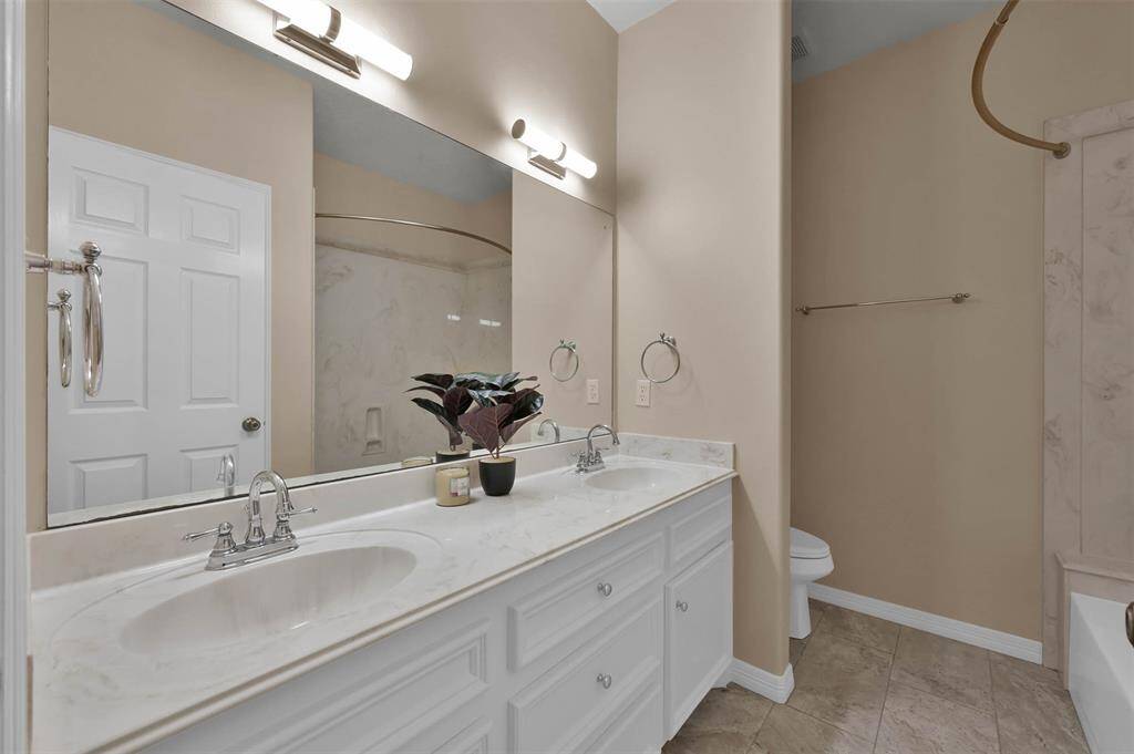 Spacious hall bathroom featuring double sinks and a convenient tub-shower combo.