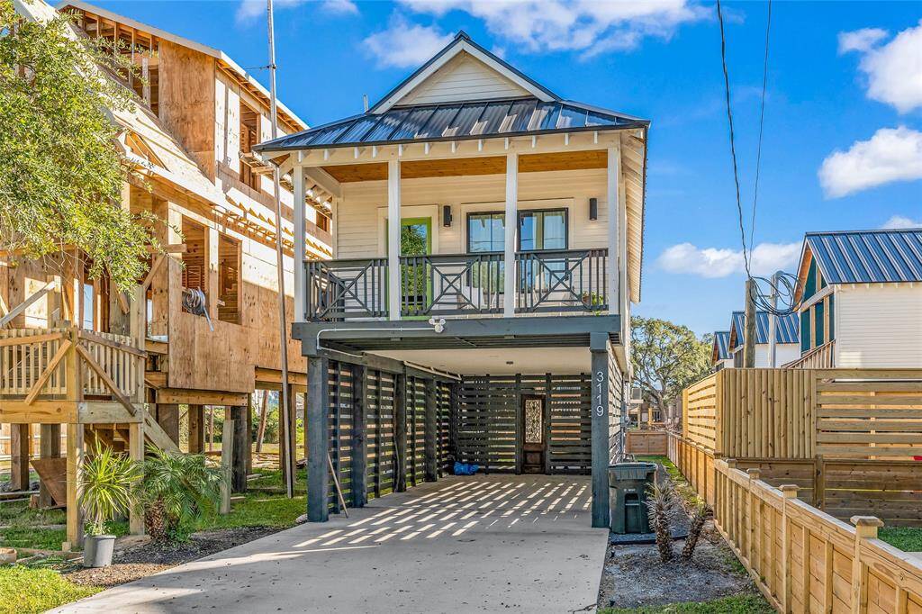 Modern elevated home with a charming front porch, metal roof, and spacious porte cache, built in 2021 this newer construction is built to exceed windstorm specifications. This home features a fenced yard, private outdoor living space with an outdoor shower a perfect place to gather after a day at the beach