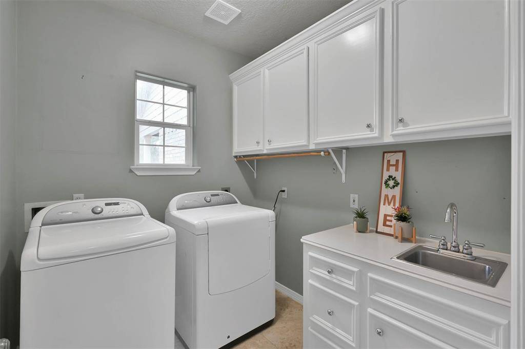 Spacious laundry room with custom cabinets, a convenient sink, and abundant natural light.