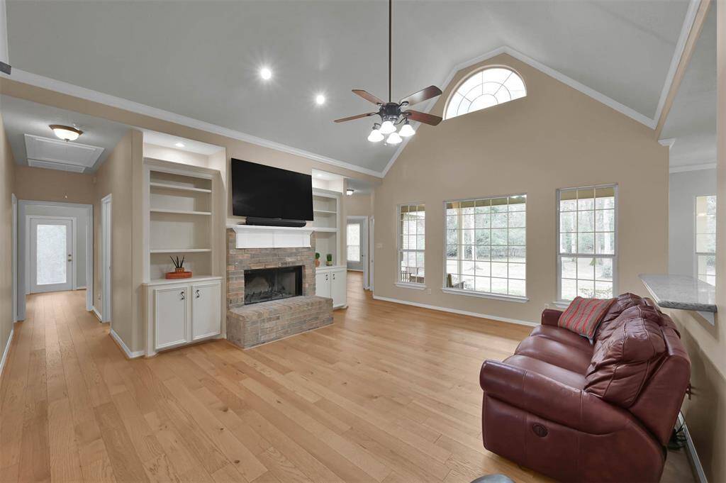 Living Room has a fireplace and custom shelving around fireplace. Windows look out onto the covered patio with large backyard