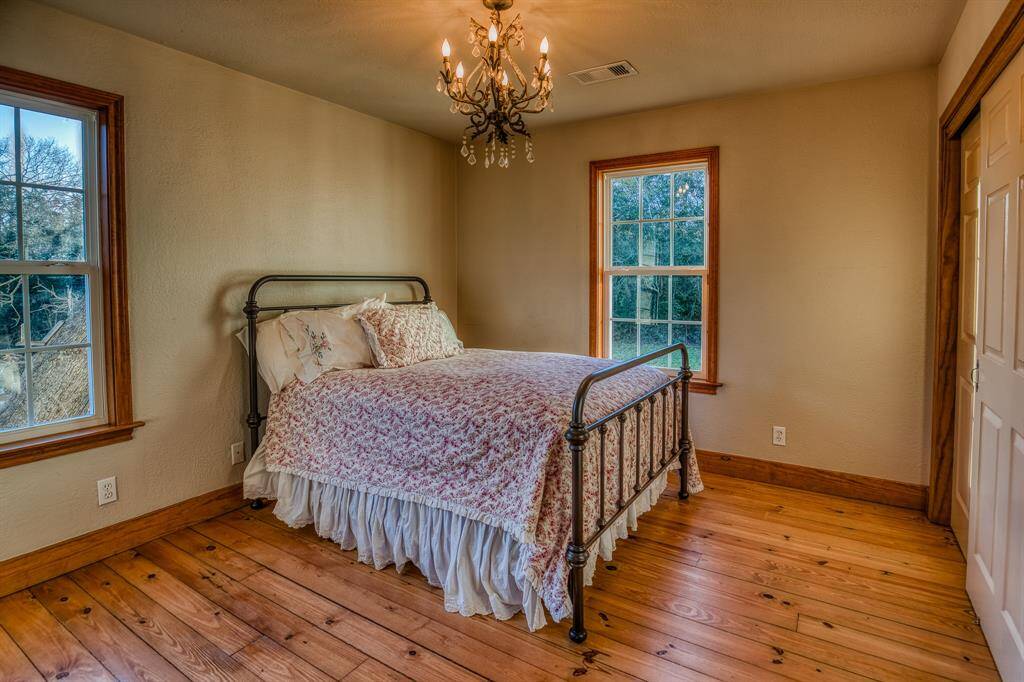 1 of 3 bedrooms. This space is used as the primary bedroom & provides lots of natural light & a touch of elegance with its own chandelier. The hardwood floors add that rustic country charm.