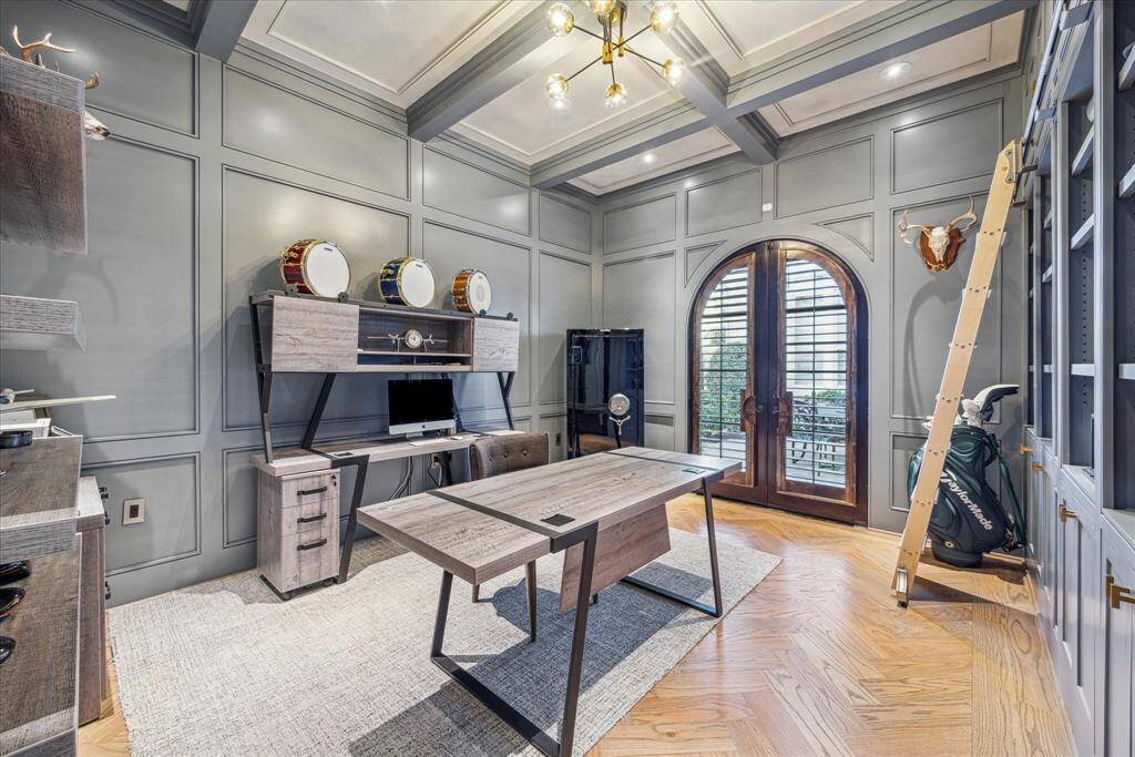 First floor library/office with double doors leading to a sitting area in the courtyard. Paneled, rolling ladder at bookshelves, and wood floors.