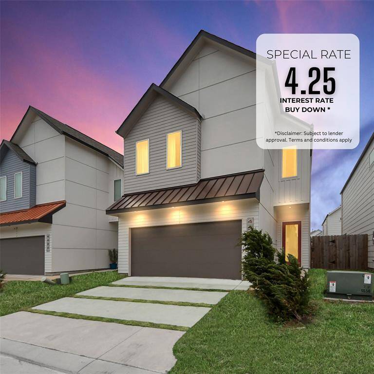 Modern two-story home with a sleek design, featuring a double garage and a well-maintained lawn. The house is part of a neat row of similar homes, offering a welcoming neighborhood feel. The warm glow from the windows suggests a cozy interior.