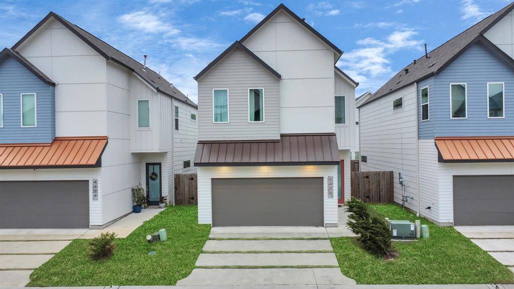 Modern two-story home with a clean, contemporary exterior. Features include a double garage, neat lawn, and a fenced backyard. Located in a row of similar styled houses, offering a cohesive neighborhood aesthetic.