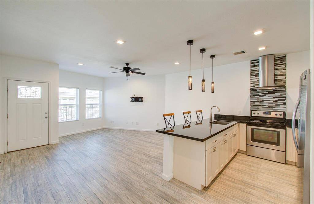 View of kitchen and living area with ample natural light from multiple windows, and a ceiling fan, creating a bright and inviting atmosphere.