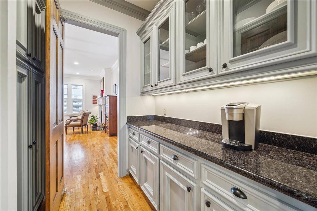The butler's pantry is designed with sleek granite countertops, elegant glass-front cabinets, and great storage space, including a convenient walk-in pantry.