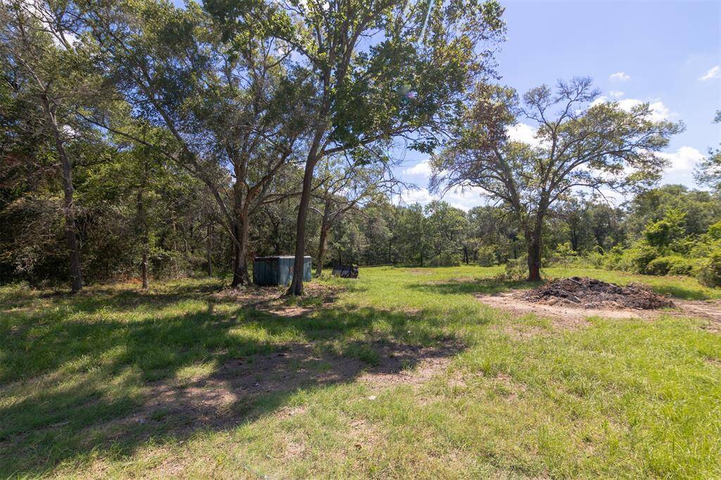 The property is partially cleared and has mature shade trees.
