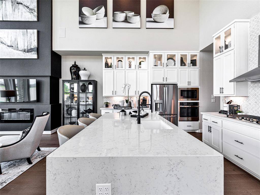 There's an open layout connecting to a stylish living area with a fireplace and contemporary decor. High ceilings and ample natural light enhance the spacious feel.