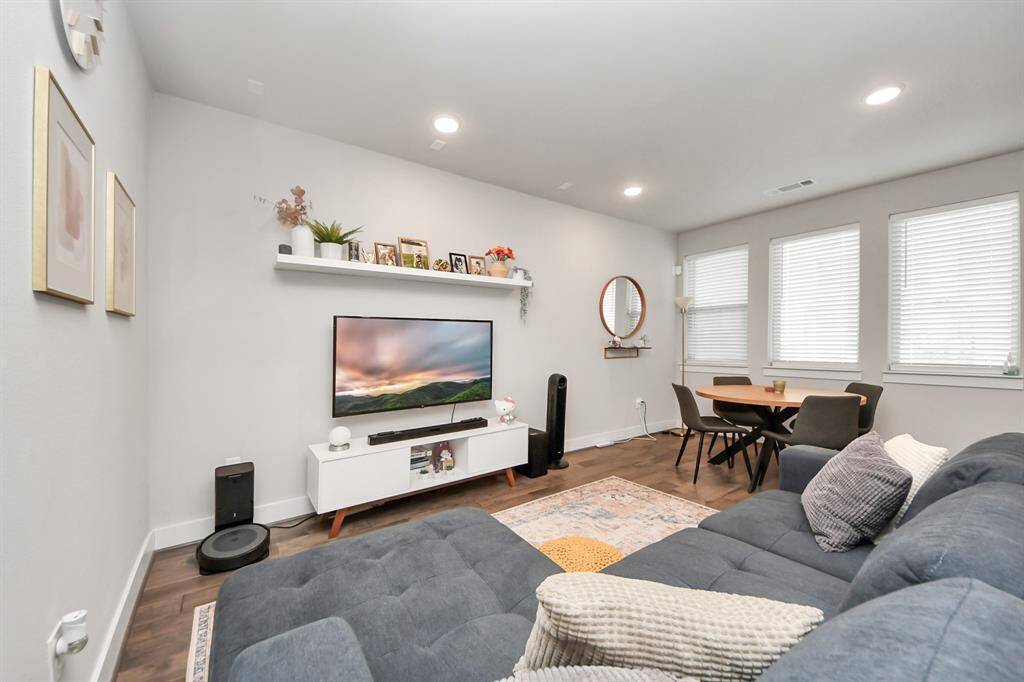 This cozy living room features a modern, open layout. Natural light pours in through multiple windows, illuminating the space. A small dining area is neatly positioned in the corner, creating a perfect blend of comfort and functionality.