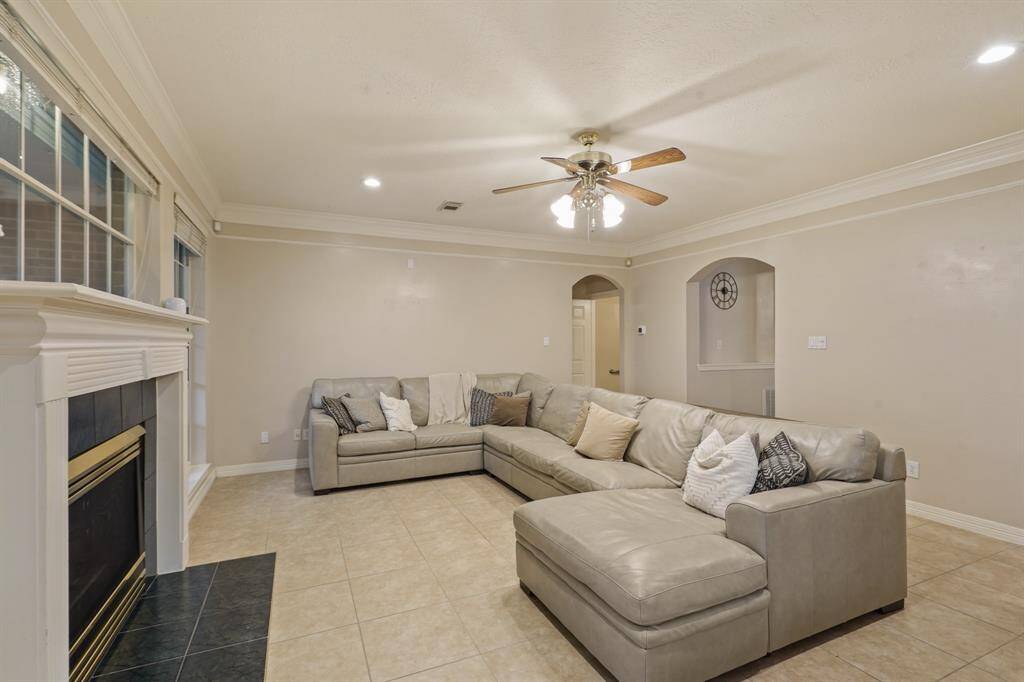 Walk through the foyer past the staircase and arrive at this incredible living room! Highlighted by crown molding details, a gorgeous fireplace and mantle, tile floors, recessed lighting, and a ceiling fan.