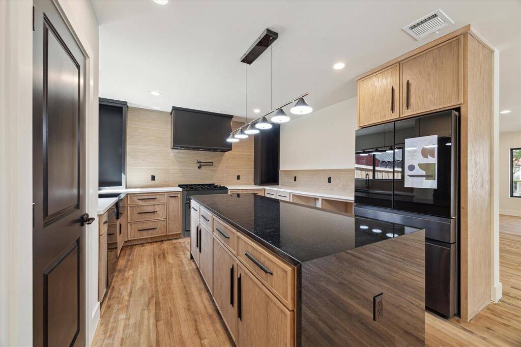 A waterfall of black granite stone serenely centers the kitchen.