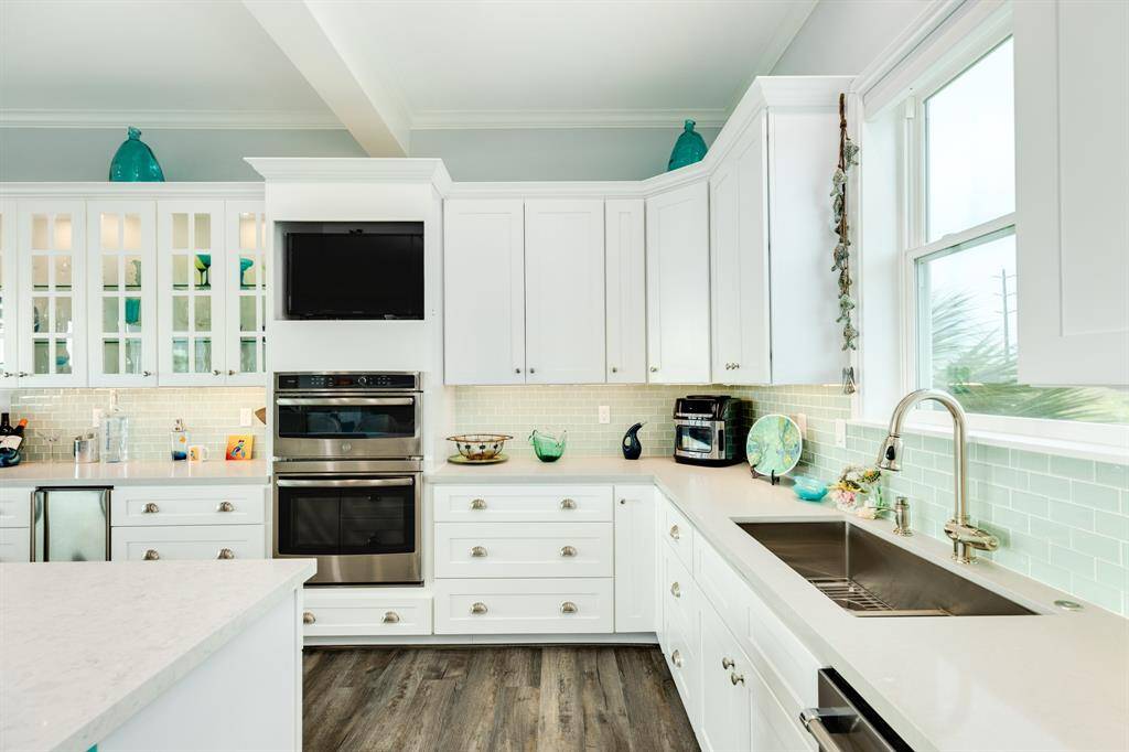 Large stainless sink, glass tile backsplash and upper & lower cabinet provide a sleek modern feel to the kitchen.