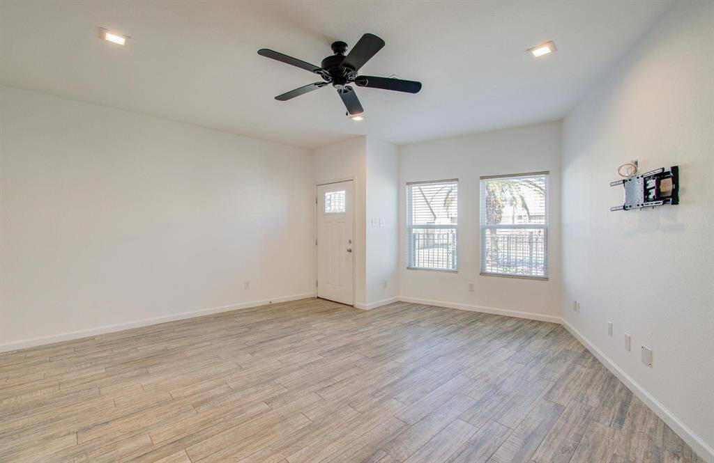 Bright, open living space with vinyl flooring, ceiling fan, and recessed lighting. Features large windows for natural light and a wall mount for a TV. Perfect for a cozy and stylish living area.