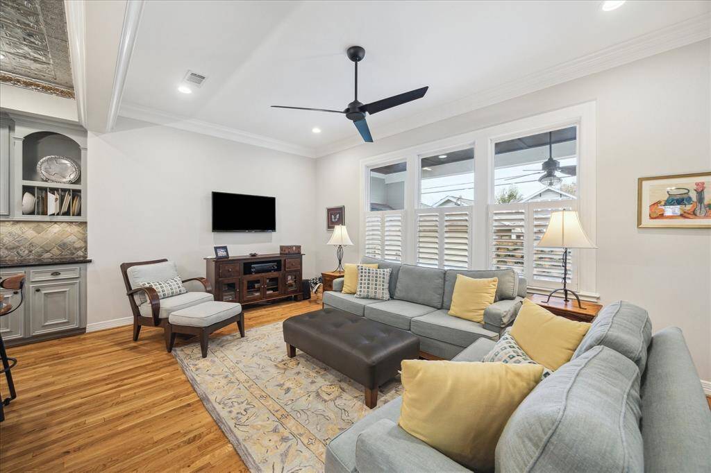 The kitchen opens directly into the den featuring recessed lighting, a ceiling fan, crown molding, and large windows that flood the room with natural light, enhancing its inviting and airy atmosphere.