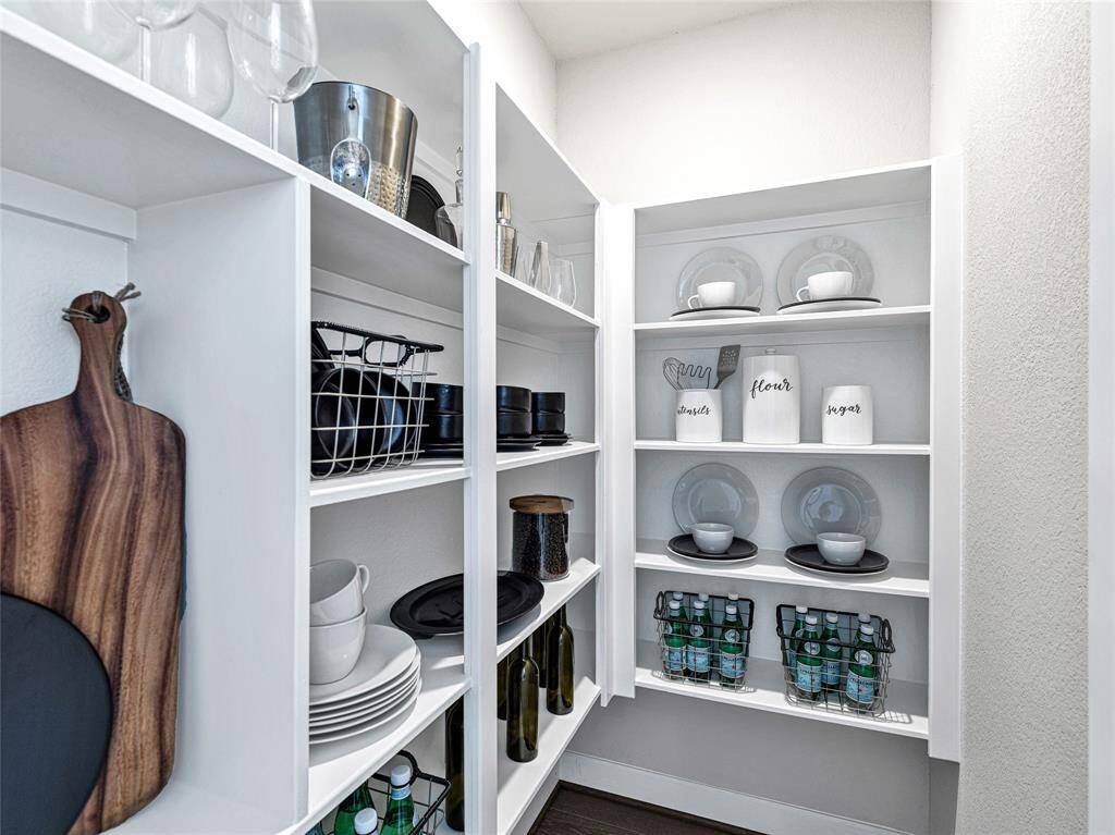 This is a well-organized pantry featuring white shelving with ample storage space for dishes, glassware, and pantry staples.
