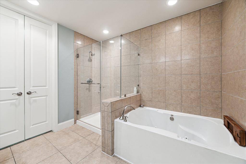 The en suite primary bath showcases a separate soaking tub and a walk-in shower, complemented by timeless tile work.