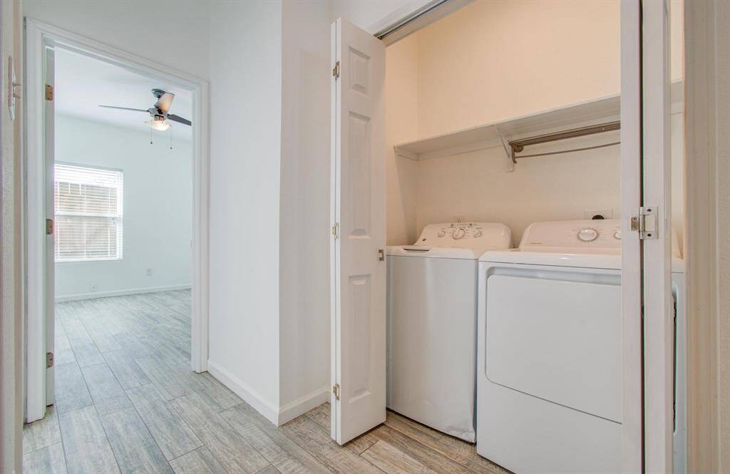 Featuring a laundry closet with a washer and dryer. Bedroom with a window and ceiling fan is also visible.