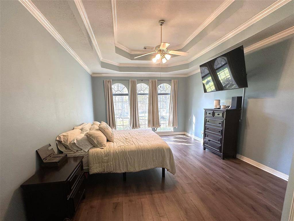 Unwind after a long day in this spacious Primary Bedroom! Featuring lots of natural light, brand new wood flooring, crown molding details, and an elegant tray ceiling with a ceiling fan.