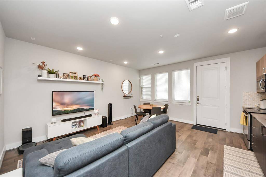 The room is bright with natural light from multiple windows. The design is contemporary and inviting, ideal for comfortable living.