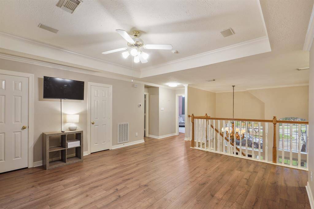 Conveniently upstairs is this fabulous game room! Complete with wood floors, a tray ceiling with a ceiling fan, and crown molding details. You can also check the foyer from the top of the room and also be mesmerized by the stunning chandelier.
