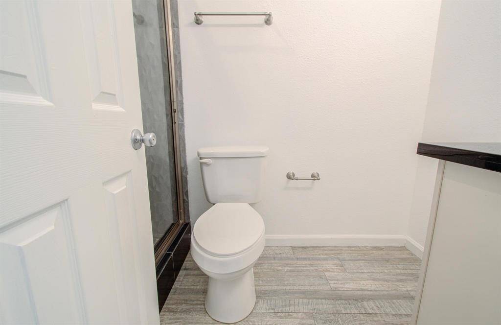 Modern bathroom with shower with a glass door, and vinyl flooring.