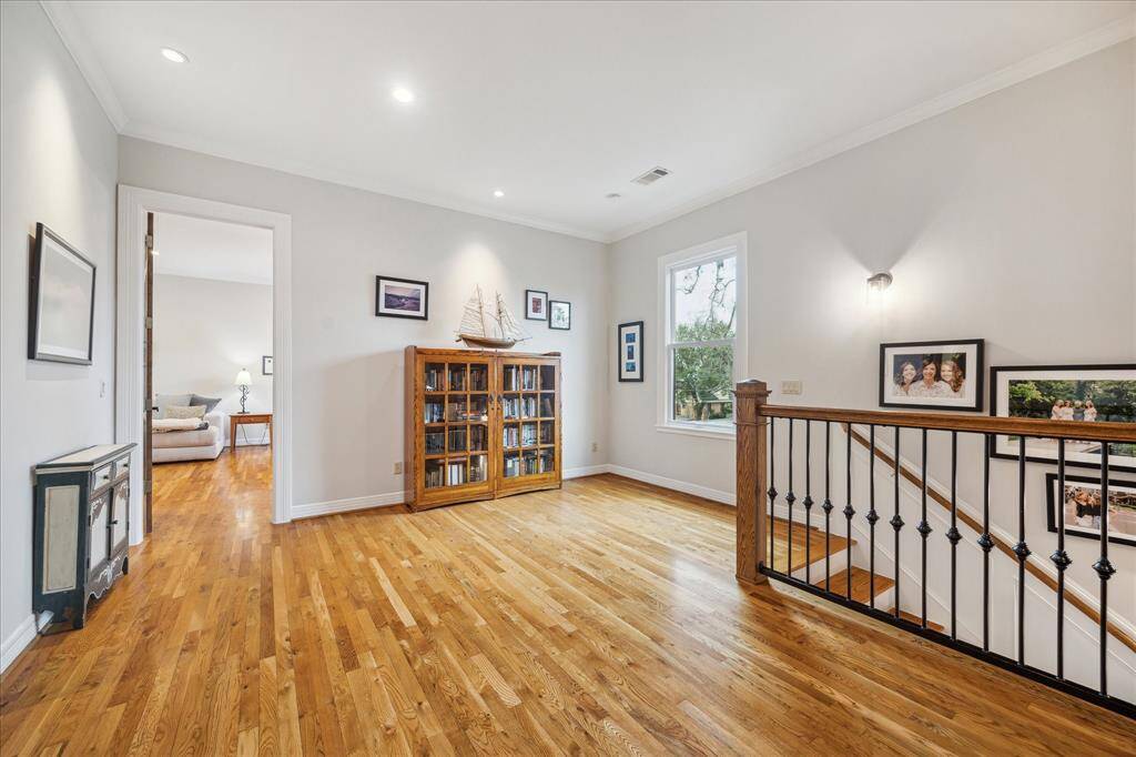 The game room area, featuring recessed lighting and wood flooring, is conveniently located just off the stairs, offering a great spot for relaxation and entertainment.
