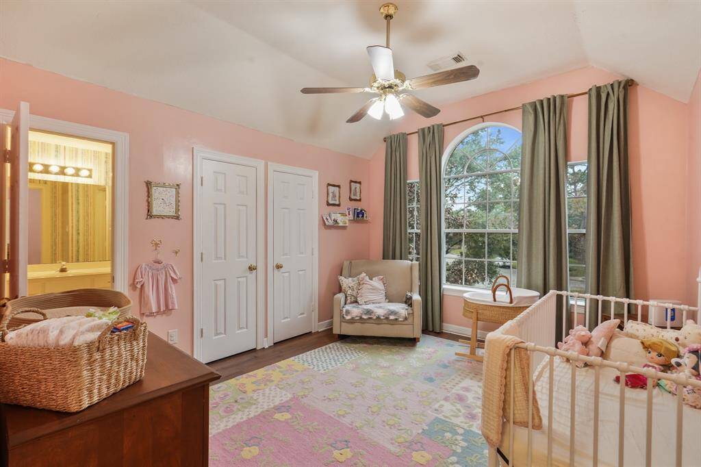 Secondary Bedroom with wood floors, a vaulted ceiling with a ceiling fan, large windows, two built-in closets, and its own en-suite bathroom.