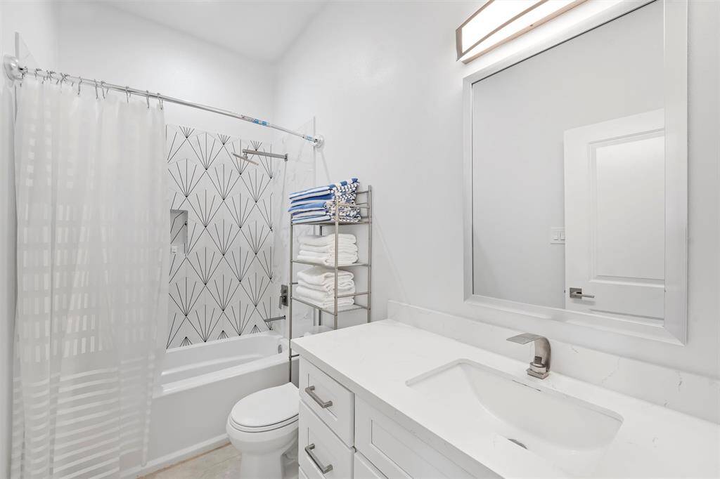 This stylish shared hall bath features modern finishes, a sleek quartz vanity, and eye-catching tile accents for a clean and sophisticated look.