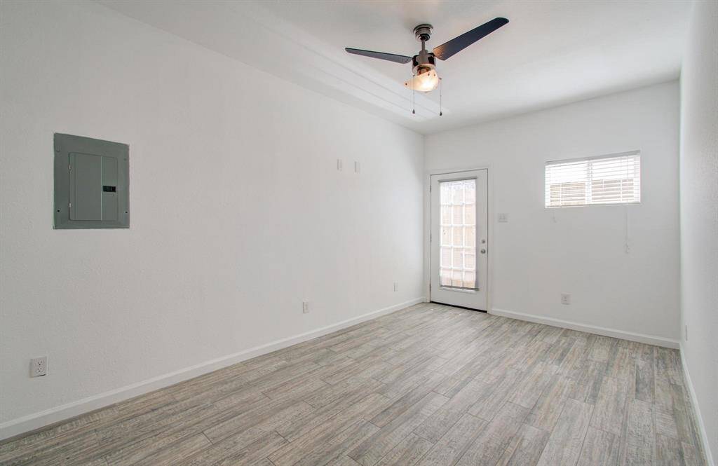 Primary bedroom features vinyl flooring, ceiling fan, ample natural light from window and glass door, and a neutral color palette.
