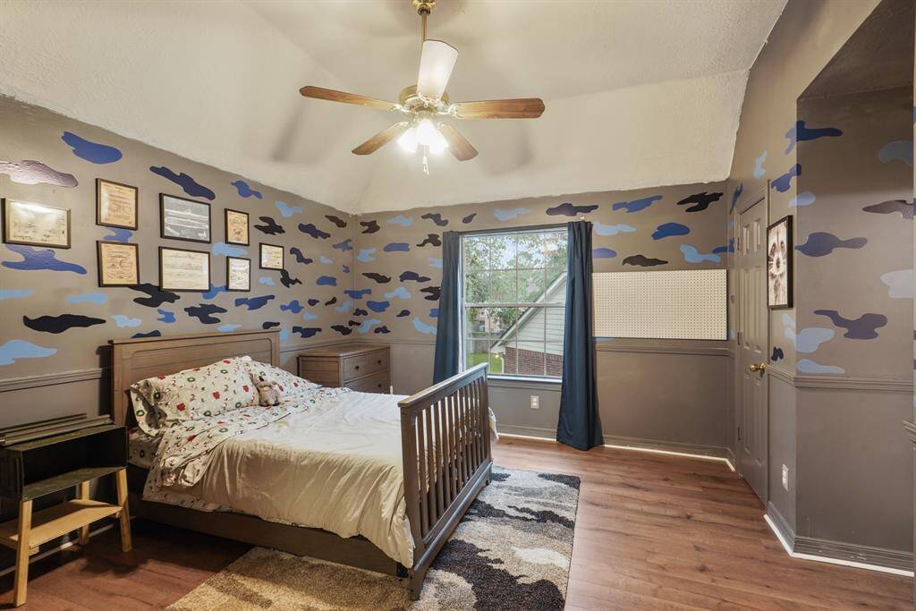 Secondary Bedroom featuring wood floors, a vaulted ceiling with a ceiling fan, a large window, and a built-in closet.
