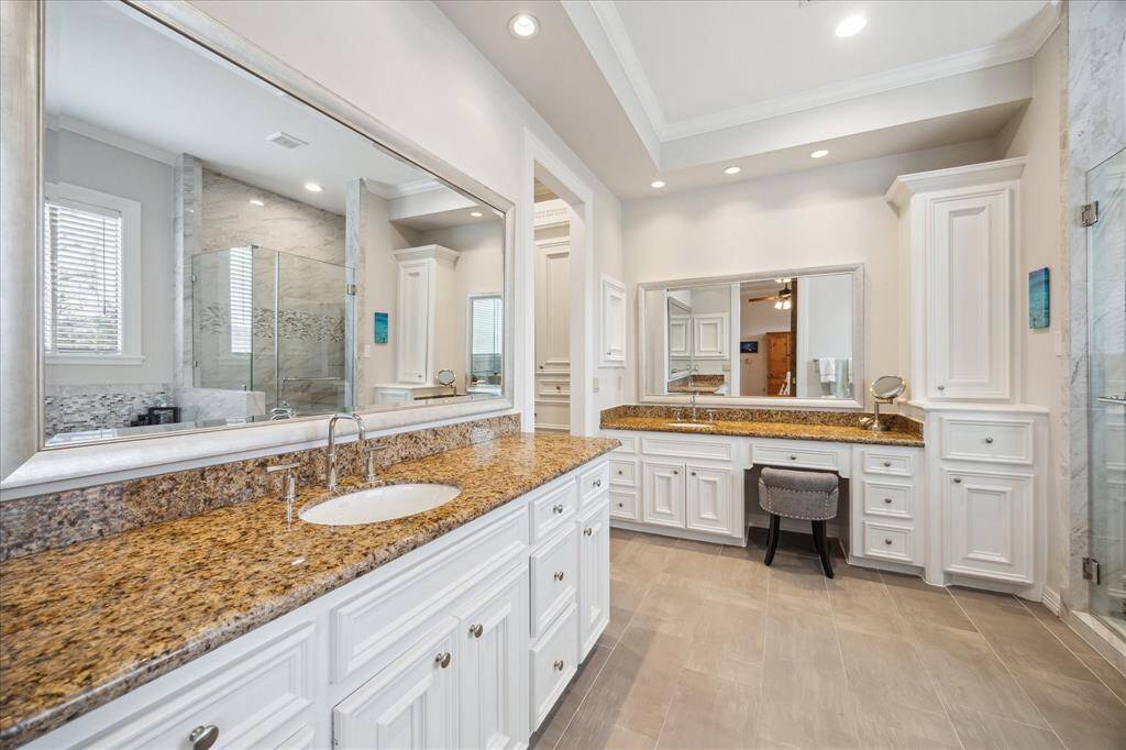 The primary bath offers double sinks, granite countertops, large mirrors, vanity space, and a spacious walk-in closet, combining style and functionality.