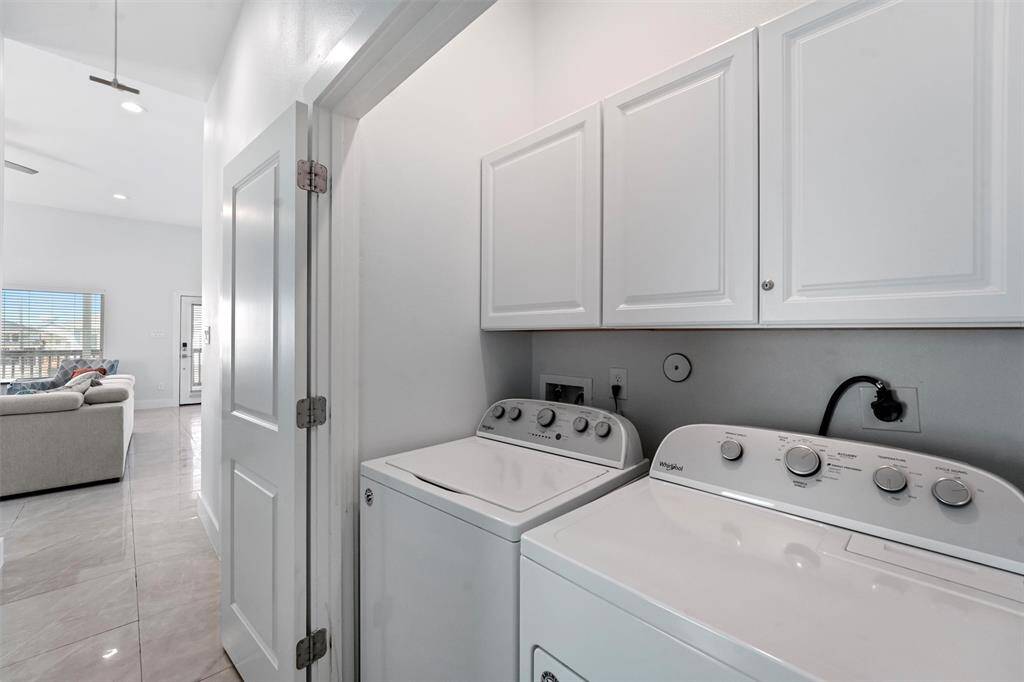 This conveniently located laundry space is tucked away in the hall, featuring built-in cabinetry for extra storage.