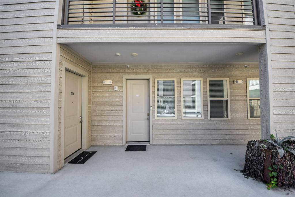 Exterior entrance of the unit. The area features a covered entryway, wood siding, and multiple windows.