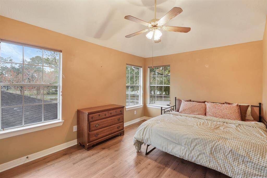 Secondary Bedroom with wood floors, large windows, and a ceiling fan.
