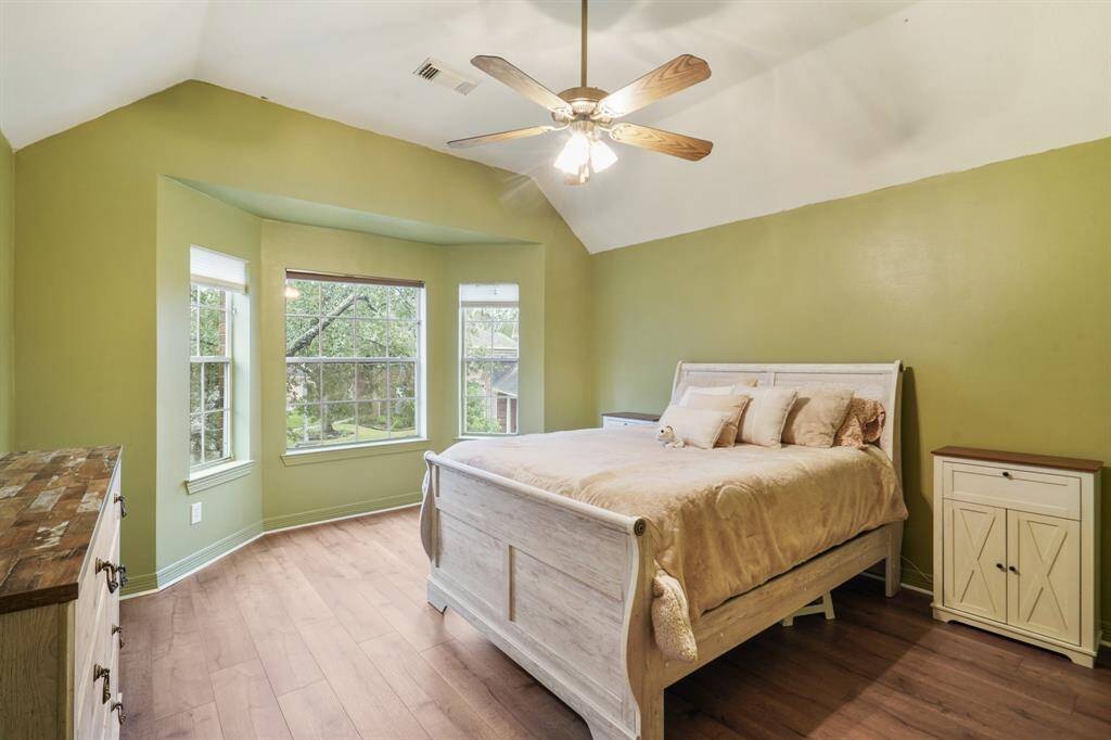Secondary Bedroom with wood floors, large windows, and a vaulted ceiling with a ceiling fan.