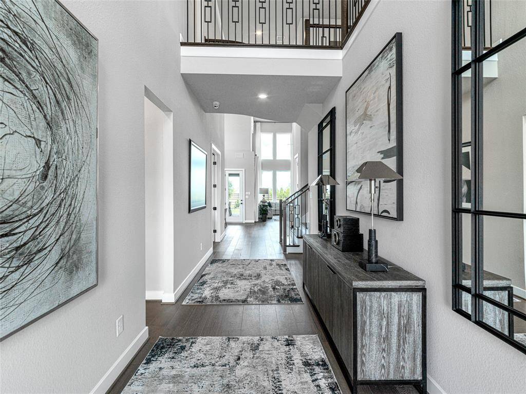 Open-concept hallway with high ceilings and stylish decor. It features a view towards a bright living area with large windows, creating an inviting and spacious ambiance.