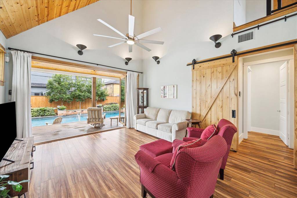 The living area of the pool house features accordion glass doors that open wide, offering an unobstructed view of the sparkling pool and seamlessly blending indoor and outdoor living.